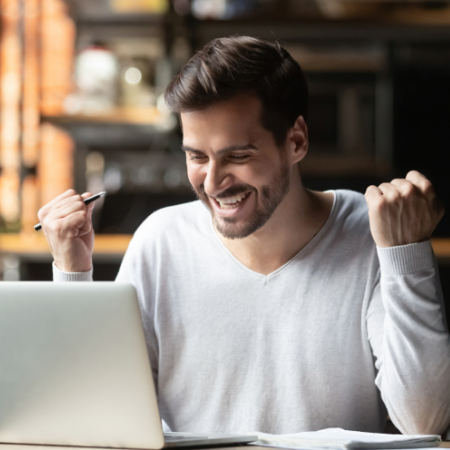 Middle eastern man fist pumping in front of a computer